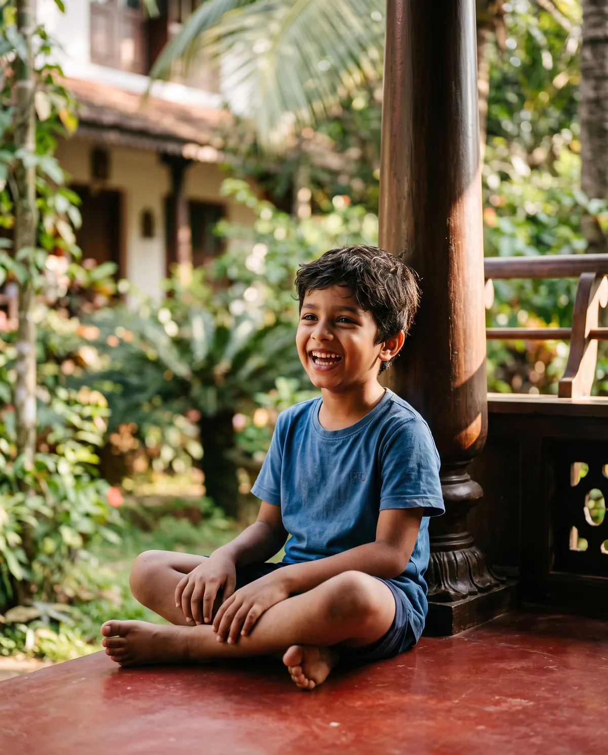 A laughing young boy on a sunlit Kerala veranda